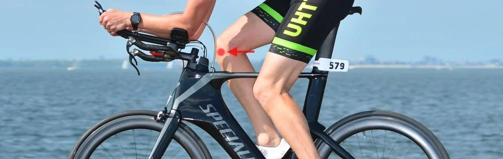 Ciclista numa bicicleta de contrarrelógio com indicação de dor no interior do joelho